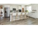 Bright kitchen featuring white cabinets, an island with seating, and hardwood floors at 9711 Palermo Ave, Indianapolis, IN 46239
