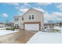 Two-story house with a brick and beige siding exterior, attached garage, and snow covered landscaping at 507 Abbywood Cir, Danville, IN 46122