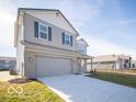Exterior view of a two-story home with gray siding, brick accents, a two-car garage, and a green lawn at 6349 Granby Dr, Whitestown, IN 46075