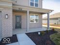 View of the front porch of a home with gray siding, brick accents, and a well-maintained front lawn at 6349 Granby Dr, Whitestown, IN 46075