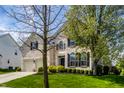 Attractive two-story brick home featuring a manicured lawn, lovely shrubbery and trees on a sunny day at 12596 Autumn Gate Way, Carmel, IN 46033
