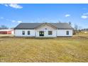 Bright modern farmhouse with a metal roof and inviting entryway is surrounded by a beautifully landscaped yard at 1600 S Morgantown Rd, Morgantown, IN 46160