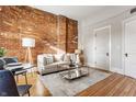 Inviting living space with exposed brick accent wall, hardwood floors, and neutral furnishings at 643 Fort Wayne Ave # H, Indianapolis, IN 46204