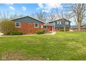 View of home with brick and siding, trimmed bushes in front, and green lawn at 8810 W Tulip Tree Dr, Muncie, IN 47304