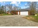 Spacious driveway leading to an attached garage with a basketball hoop and a well-maintained lawn at 8810 W Tulip Tree Dr, Muncie, IN 47304