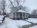 Tan house with white trim and porch, nestled on a snow-covered lot at 1128 N Holmes Ave, Indianapolis, IN 46222