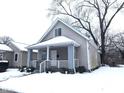 Tan house with white trim and porch, nestled on a snow-covered lot at 1128 N Holmes Ave, Indianapolis, IN 46222