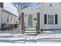 Quaint white house with teal door, covered porch and snowy yard at 1218 N Grant Ave, Indianapolis, IN 46201