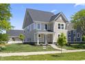 Charming two-story home with a manicured lawn, gray siding and a quaint covered front porch at 1833 Luther St, Indianapolis, IN 46203