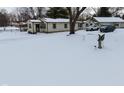 Ranch home with a snow covered yard and angel statue at 2515 Fairfax Rd, Indianapolis, IN 46227