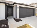 Front exterior featuring a black garage door, white siding, and walkway to the front door at 3201 W Keepsake Ln, Monrovia, IN 46157