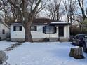 A cozy home with snowy front yard featuring mature trees and black window shutters at 3951 N Pasadena St, Indianapolis, IN 46226