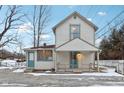Two-story white house with front porch, snowy yard, and fence at 4702 Michigan Rd, Indianapolis, IN 46228