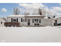 White ranch home with covered porch and snow covered yard at 5150 Atherton N Dr, Indianapolis, IN 46219