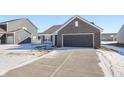 Gray and brick house exterior with a dark gray garage door and snowy yard at 943 Aurora Ln, Franklin, IN 46131