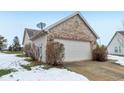 Attached garage with light beige door and brick exterior at 11537 Jagged Rock Ct, Fishers, IN 46037