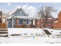 Snow-covered yard, blue house with brick foundation and snowy front steps at 1302 Laurel St, Indianapolis, IN 46203