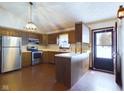 L-shaped kitchen with wood cabinets, stainless steel appliances, and brick flooring at 2584 W Mercer Ln, Pendleton, IN 46064