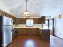 L-shaped kitchen with wood cabinets, stainless steel appliances, and brick flooring at 2584 W Mercer Ln, Pendleton, IN 46064
