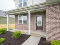 Inviting front porch with brick accents, supported columns, and well-manicured landscaping at 7824 Magnolia St, New Palestine, IN 46163