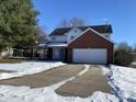 Two-story brick home with attached garage, partially covered porch, and snowy yard at 8531 Friendship Ln, Indianapolis, IN 46217