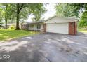 Brick ranch home with a driveway and mature trees at 9876 Woodbriar Ln, Carmel, IN 46280
