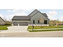 Gray farmhouse with a two car garage and large driveway. Landscaped yard and stone accents at 14028 Grannan Ln, Carmel, IN 46074