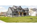 Gray farmhouse with a large front porch, stone accents, and a neatly landscaped yard at 14028 Grannan Ln, Carmel, IN 46074