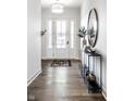 Elegant foyer with a white front door, wood floors, stylish console table, and a decorative mirror at 20188 Hampton Park Dr, Westfield, IN 46074