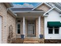Charming front porch with columns, brick accents, decorative potted plants and a delightful green awning at 4232 Bunting Ln, Columbus, IN 47203
