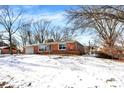 Side view of a brick ranch house on a snowy lot with mature trees at 8408 Valley Estates Dr, Indianapolis, IN 46227