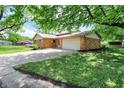 Home featuring a spacious driveway and lush green trees, offering shade and curb appeal at 9157 Neptune Dr, Indianapolis, IN 46229