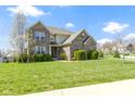 Beautiful two-story home featuring a well-manicured lawn, green shrubs, and blossoming trees on a sunny day at 11383 Sea Side Ct, Fishers, IN 46040