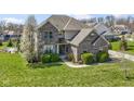 Attractive two-story brick home with manicured lawn and sidewalk, surrounded by mature trees in full bloom at 11383 Sea Side Ct, Fishers, IN 46040