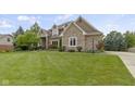 Beautifully landscaped brick home with a lush green lawn and mature trees on a bright day at 14832 Sulky Way, Carmel, IN 46032