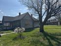 Weathered wood house with a large tree and small flowering bush at 1520 N Bancroft St, Indianapolis, IN 46201
