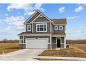 Two-story home featuring a two-car garage, and gray siding with white trim, set against a partly cloudy blue sky at 2310 Marjorie Way, Shelbyville, IN 46176