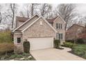 Two-story brick home with attached garage, complemented by a landscaped front yard with colorful plants at 10402 Shakamak Way, Indianapolis, IN 46239