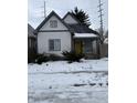 Charming white house with gray accents, yellow door, and snowy yard at 243 E Caven St, Indianapolis, IN 46225