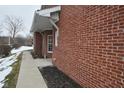 Brick side of house with walkway and landscaping partially covered in snow at 8042 Hazen Way, Indianapolis, IN 46216