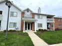 Inviting two-story condo featuring a landscaped yard, covered entry and light gray siding at 8104 Glenwillow Ln # 208, Indianapolis, IN 46278