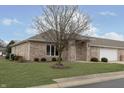 Charming brick home with a large tree in the yard and an attached two-car garage at 116 Jasper Way, Anderson, IN 46012