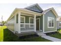 Inviting green home featuring a cozy front porch and manicured garden, ideal for relaxation at 1407 N Pershing Ave, Indianapolis, IN 46222