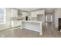 Bright kitchen boasts white cabinets, a large island, and vinyl flooring at 14403 Bishop Birch Pl, Carmel, IN 46032