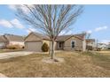 View of home featuring neutral exterior, including a two car garage, small tree, and winter lawn at 352 Parkview Dr, Danville, IN 46122
