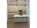 Modern kitchen with gray cabinets, stainless steel appliances, quartz countertops, and hardwood flooring at 525 Gilder Dr, Carmel, IN 46032