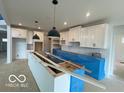 Spacious kitchen with white cabinets, a large island, and modern pendant lighting at 9497 Dogwood Dr, McCordsville, IN 46055
