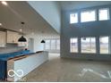 Open-concept living area with large windows, soaring ceilings, and modern pendant lighting at 9497 Dogwood Dr, McCordsville, IN 46055