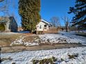 House with wooden deck, snow-covered yard, and tall evergreen tree at 2104 Drexel Dr, Anderson, IN 46011