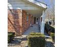 Covered front porch with white pillars, red brick exterior, and manicured hedges at 2509 W Euclid Ave, Muncie, IN 47304